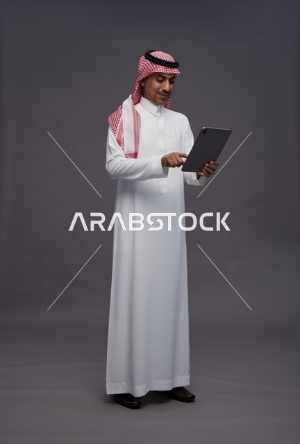 Saudi Man Using Digital Tablet on Grey Background