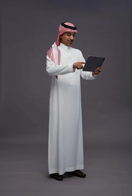 Saudi Man Using Digital Tablet on Grey Background