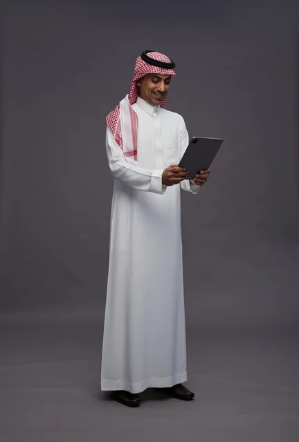 Saudi Man in Traditional Thobe Using Digital Tablet