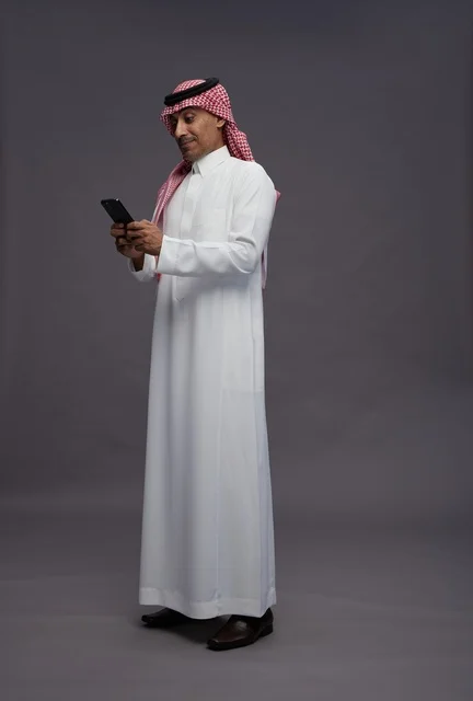 Saudi Man in Traditional Thobe Using Smartphone