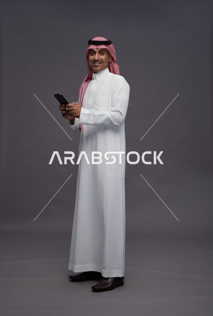 Saudi Man in Traditional Thobe Holding Smartphone