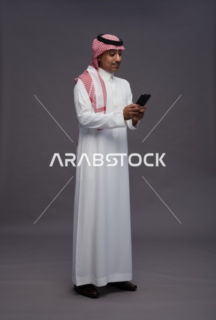 Saudi Man in Traditional Thobe Using Smartphone