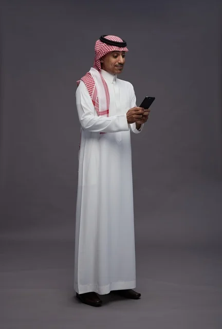 Saudi Man in Traditional Thobe Using Smartphone