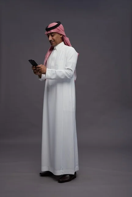 Saudi Man in Traditional Thobe Using Smartphone
