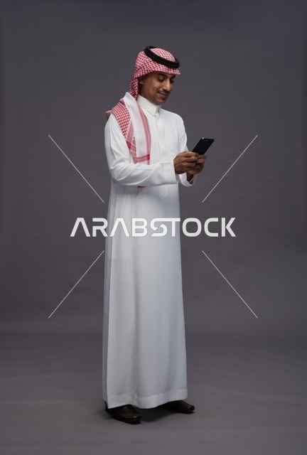 Saudi Man in Traditional Thobe Using Smartphone