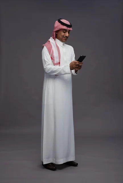Saudi Man in Traditional Thobe Using Smartphone