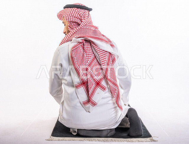 بورتريه من الخلف لرجل عربي سعودي خليجي يرتدي الثوب الأبيض والشماغ يؤدي الصلاه, الجلوس على سجادة الصلاه, الإكثار من ذكر الله تعالى, الإستغفار والدعاء, الإجتهاد في العباده, التقرب الى الله تعالى في شهر رمضان المبارك, جمعه مباركه, إسلاميات وعبادات