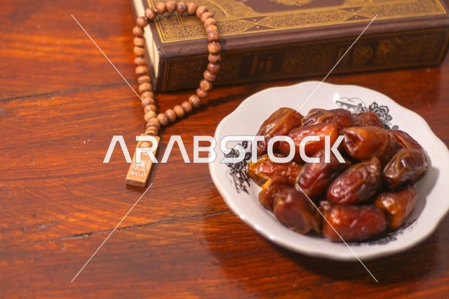 تمر رمضان مع المصحف الشريف على طاولة خشبية