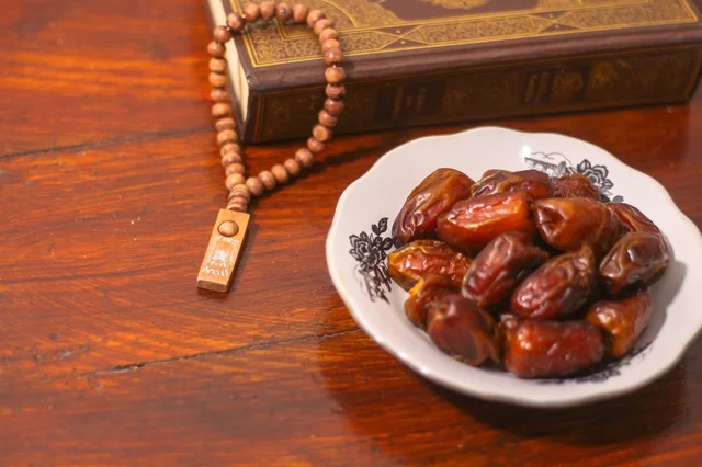 تمر رمضان مع المصحف الشريف على طاولة خشبية