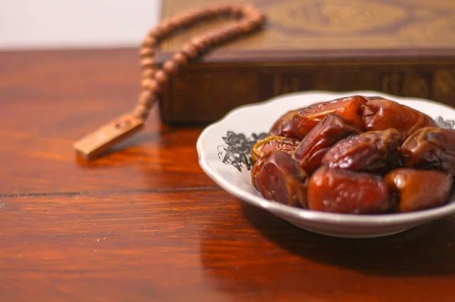 تمر رمضان مع المصحف والمسبحة على طاولة خشبية