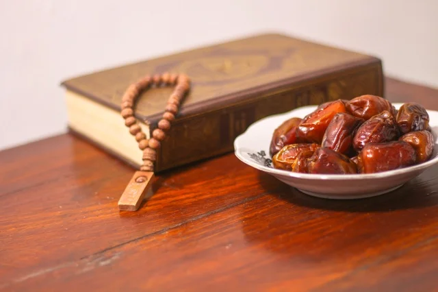 تمور رمضان مع المصحف الشريف ومسبحة خشبية على طاولة