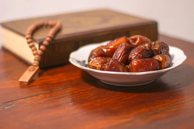 تمور رمضان والمصحف الشريف والسبحة على طاولة خشبية