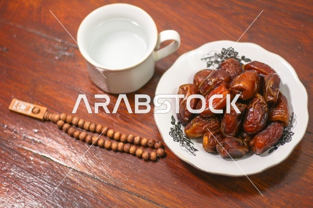 Ramadan Dates and Water with Prayer Beads on Wood