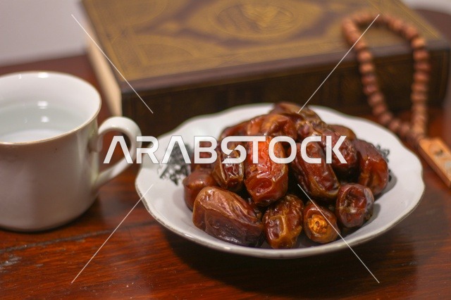 تمر رمضان مع المصحف الشريف وكوب ماء