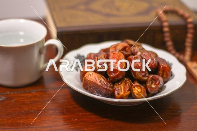 تمر رمضان مع كوب ماء ومصحف