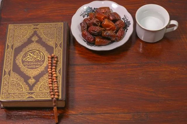 القرآن الكريم مع التمر والماء على طاولة خشبية فى اجواء رمضانية