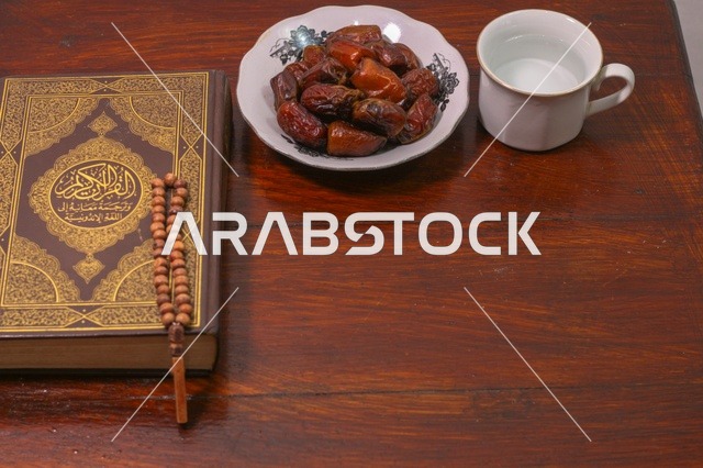 مصحف كريم مع تمر وسبحة على طاولة خشبية فى اجواء رمضانية
