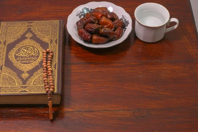 مصحف كريم مع تمر وسبحة على طاولة خشبية فى اجواء رمضانية