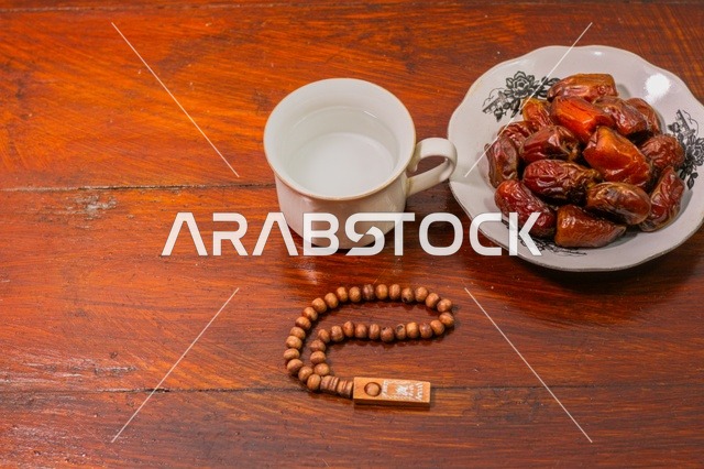 Ramadan Dates Water and Prayer Beads on Wooden Table