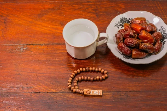 Ramadan Dates Water and Prayer Beads on Wooden Table