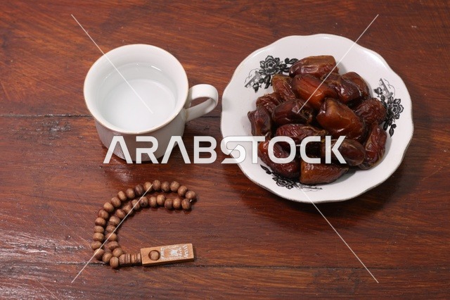تمر رمضان وكوب ماء مع مسبحة خشبية فى اجواء رمضانية