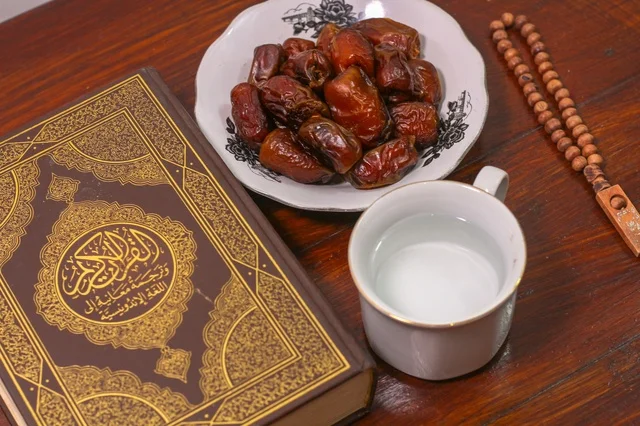 A noble Quran with dates and water on a wooden table for Ramadan iftar.