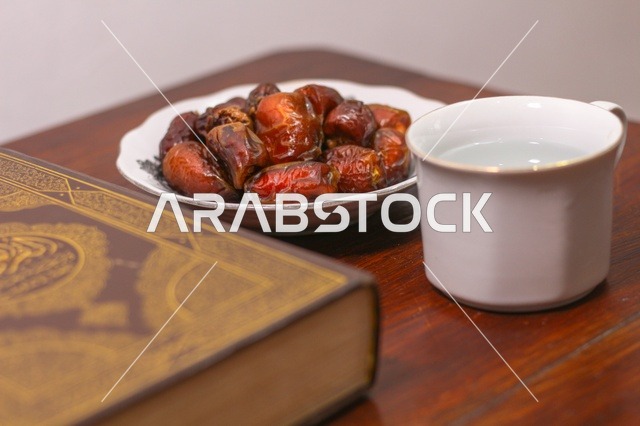 تمر وماء مع المصحف الشريف على طاولة رمضانية