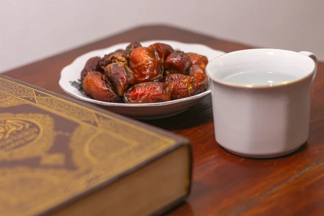 تمر وماء مع المصحف الشريف على طاولة رمضانية