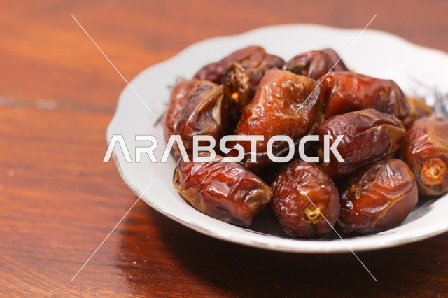 تمر مجفف في صحن على طاولة خشبية لافطار رمضان