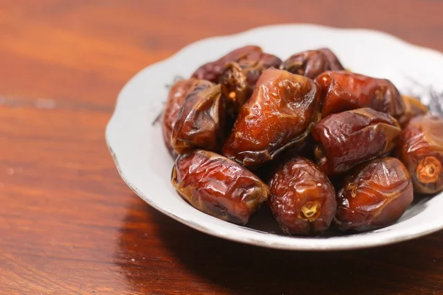 تمر مجفف في صحن على طاولة خشبية لافطار رمضان