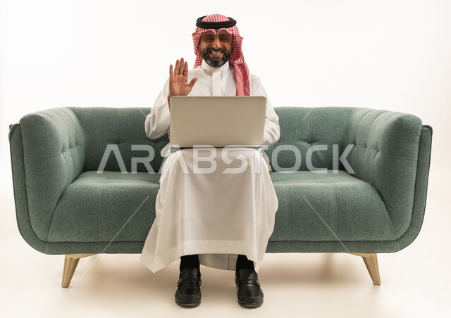 رجل سعودي يستخدم اللابتوب على أريكة خضراء