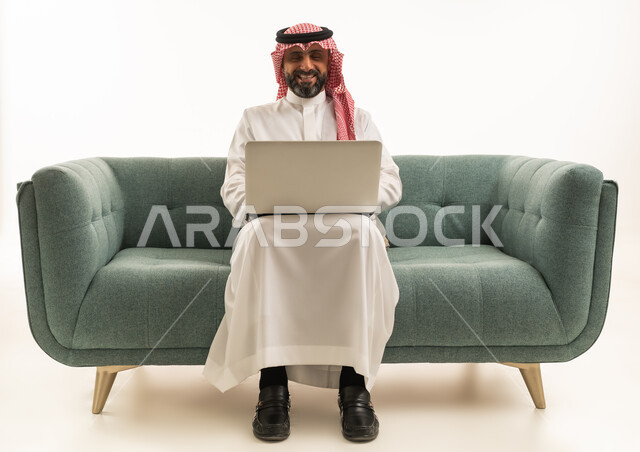 Saudi Man Using Laptop on Green Sofa