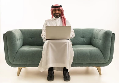 Saudi Man Using Laptop on Green Sofa