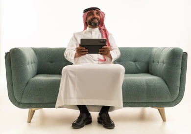 Saudi Man with Tablet on Green Sofa