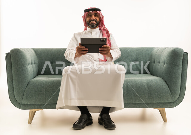 Saudi Man Using Tablet on Green Sofa