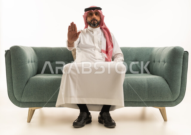 رجل سعودي بالزي التقليدي يقوم بإيماءة التوقف