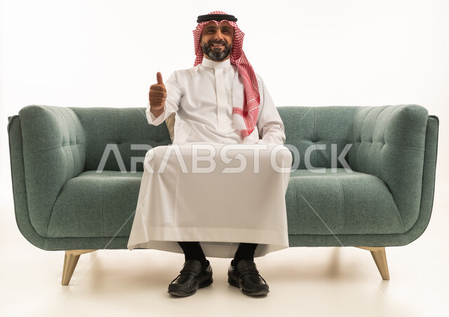 رجل سعودي على أريكة مع إيماءة الإبهام للأعلى