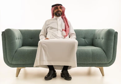 Saudi Man in Traditional Dress Sitting on Green Sofa