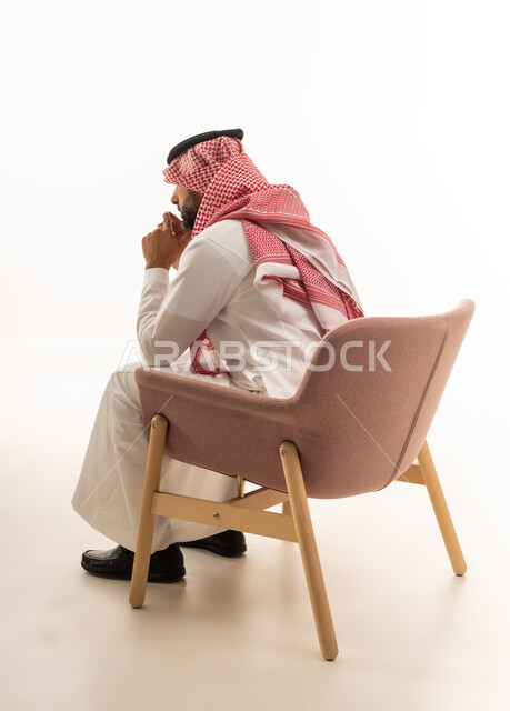رجل سعودي بالثوب التقليدي يجلس مفكراً على كرسي