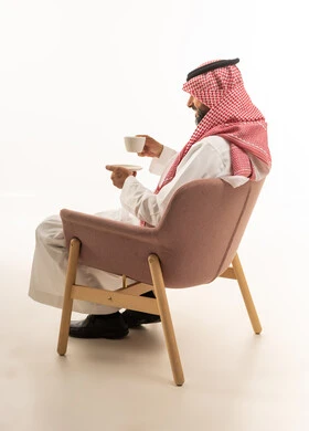 Saudi Man Holding Coffee Cup in Modern Chair