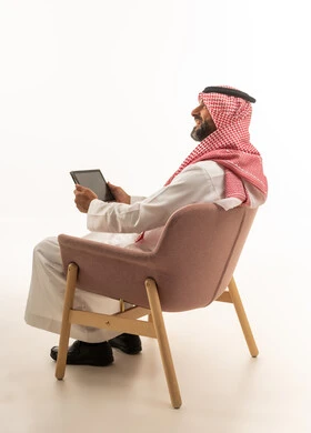 رجل سعودي بالزي التقليدي يستخدم جهاز لوحي