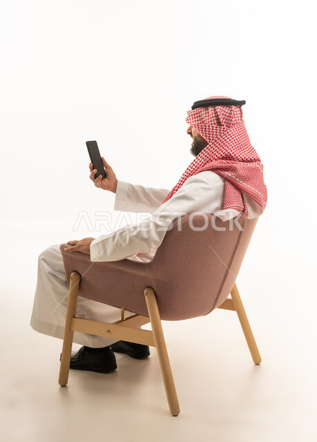 رجل سعودي بالزي التقليدي يستخدم الهاتف الذكي