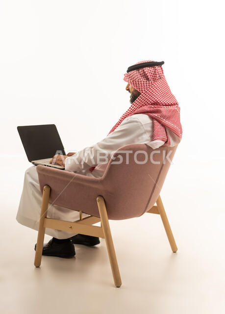 Saudi Man Using Laptop in Pink Armchair Studio Shot