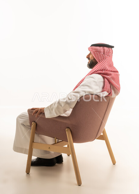 رجل سعودي بالثوب التقليدي يجلس على كرسي عصري