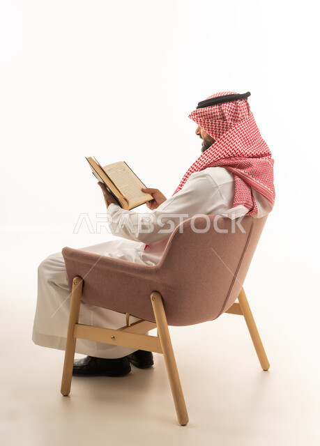 رجل سعودي بالزي التقليدي يقرأ كتاباً