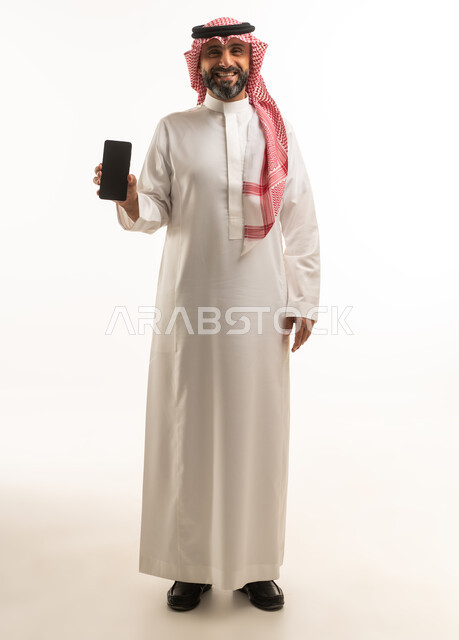 رجل سعودي بالزي التقليدي يحمل هاتف ذكي