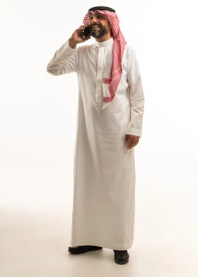 Saudi Man in Traditional Thobe Talking on Smartphone
