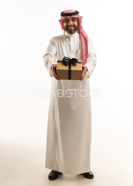 رجل سعودي بالزي التقليدي يحمل صندوق هدايا