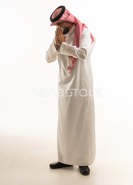 رجل سعودي بالزي التقليدي يمسح أنفه بمنديل ورقي مريض