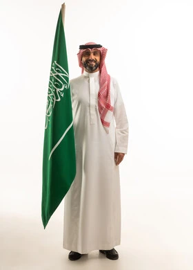 رجل سعودي يحمل العلم الوطني في استوديو